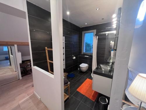 a bathroom with a toilet and a black wall at Villa Omaha in Saint-Laurent-sur-Mer
