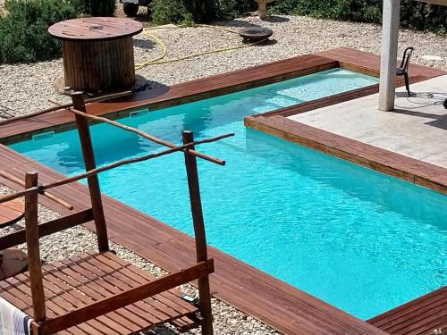 une petite piscine avec une terrasse en bois et un banc dans l'établissement MAS GAUDY Villa Piscine au cœur des vignes, à Bessan