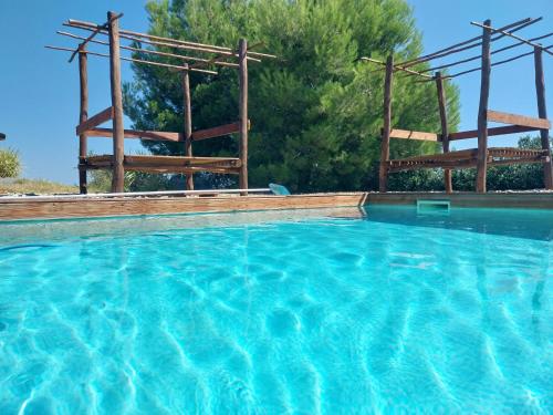 une grande piscine avec deux structures en bois dans l'établissement MAS GAUDY Villa Piscine au cœur des vignes, à Bessan