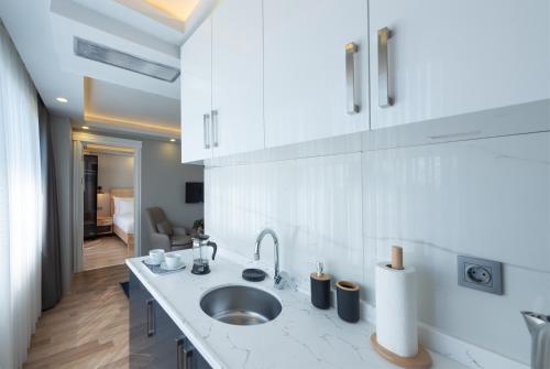 una cocina blanca con fregadero y una habitación en Art Karaköy Suites, en Estambul