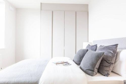 uma cama branca com almofadas cinzentas em cima em Luxury Apartment Top Location RDS, Aviva 5 min walk em Dublin
