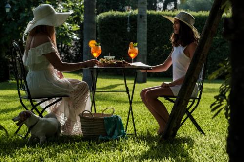 two women sitting at a table with food and a dog at Case Di Latomie in Castelvetrano Selinunte