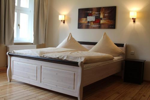 1 cama con sábanas blancas y almohadas en una habitación en Landgasthof Rieben, en Beelitz