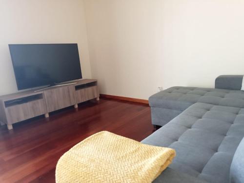 a living room with a couch and a flat screen tv at Sunrise Apartment in Caniço