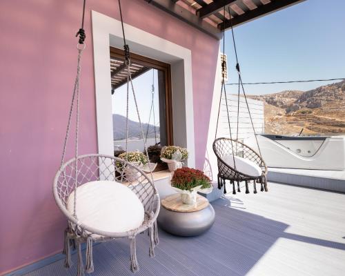 a porch with three chairs and a swing at Happinest Private Suite with Jacuzzi in Kalymnos