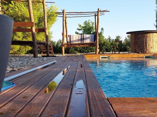 une terrasse en bois à côté d'une piscine avec une chaise dans l'établissement Domaine Mas Gaudy Villa Charme Piscine & Clim, à Bessan