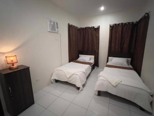 - une chambre avec deux lits et une lampe dans l'établissement Casa Via: Cozy 3 Bedroom Home in Bacolod with Parking, à Bacolod