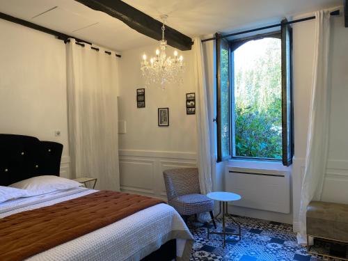 Schlafzimmer mit einem Bett, einem Fenster und einem Kronleuchter in der Unterkunft Chambre d'hôte 1787 : Les Terrasses des Pyrénées in Laloubère
