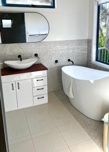 a bathroom with a white tub and a sink at Cloud Nine Apartment @ Tamar Ridge in Grindelwald