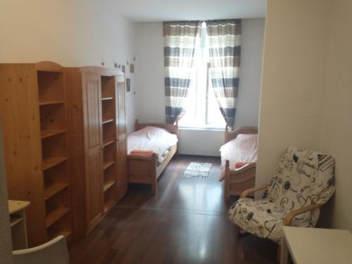 um pequeno quarto com uma cama, uma cadeira e uma janela em 8 min to Castel & Main Square na Cracóvia