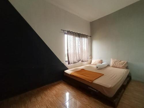 a small bedroom with a bed with white sheets and a window at Villa Cisarua Kerucut in Brujul