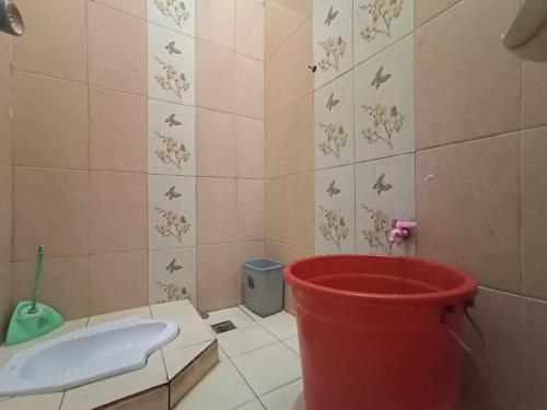 a red bucket in a bathroom with a toilet at Villa Cisarua Kerucut in Brujul