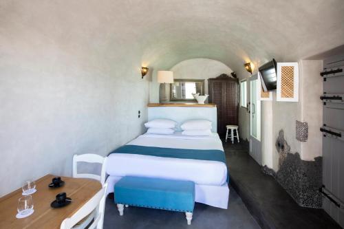 a hotel room with a bed and a desk and a bed at Ducato di Oia - Adults Only in Oia