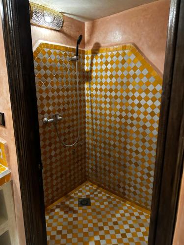 a bathroom with a shower with a checkered floor at Dar Hassan Merzouga in Merzouga