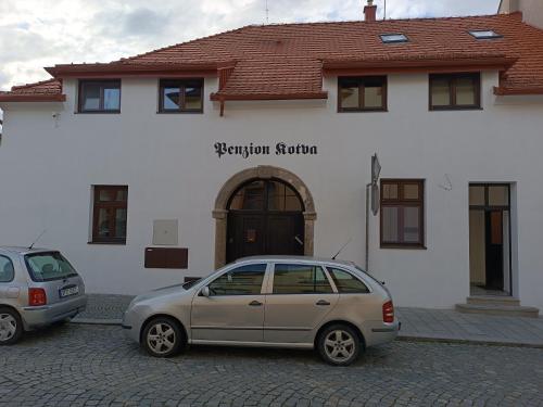 two cars parked in front of a white building at Penzion Kotva in Klatovy