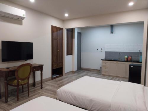 a bedroom with a bed and a desk and a television at An Nhiên Villa Hotel in Phú Mỹ