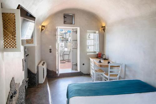 a room with a bed and a table and a door at Ducato di Oia - Adults Only in Oia