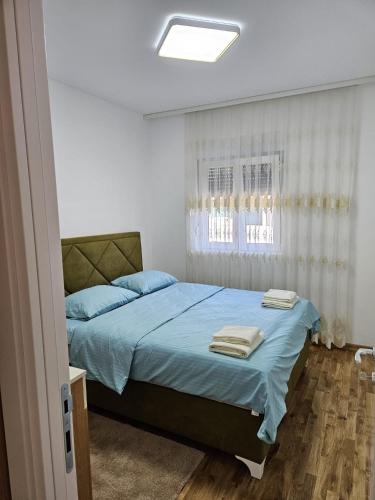 a bedroom with a bed with blue sheets and a window at Apartman Meggy in Belgrade