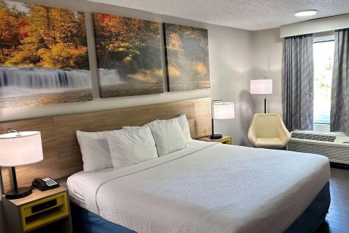 ein Hotelzimmer mit einem Bett und Gemälden an der Wand in der Unterkunft Days Inn by Wyndham Columbia NE Fort Jackson in Columbia