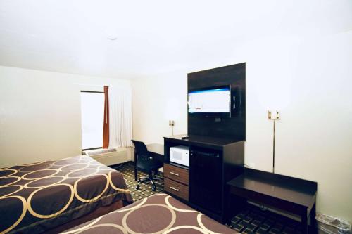 a hotel room with a bed and a dresser and a television at Super 8 by Wyndham Crossville TN in Crossville