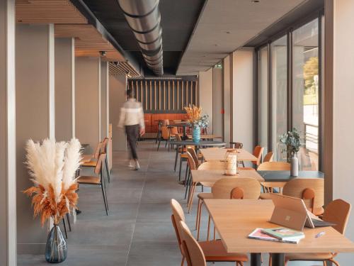 a person walking through a restaurant with tables and chairs at ibis Styles Fontenay in Fontenay-sous-Bois