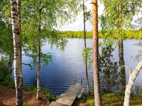 a wooden bench sitting on the side of a lake at Holiday Home Havukka by Interhome in Visulahti