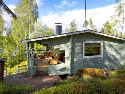 a tiny house with a deck in the woods at Holiday Home Havukka by Interhome in Visulahti