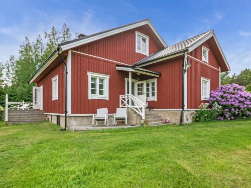 a red house with two white chairs on a yard at Holiday Home Villa nennebo by Interhome in Förby