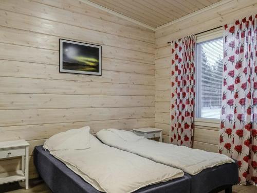 a bedroom with a bed in a wooden wall at Holiday Home Levin revontulitaivas a by Interhome in Köngäs