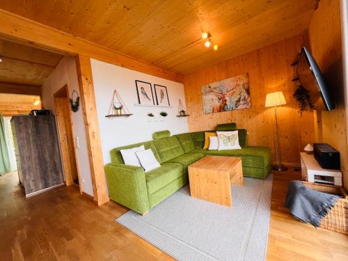 uma sala de estar com um sofá verde e uma mesa em Chalet Klippitz - Perle by Interhome em Klippitztorl