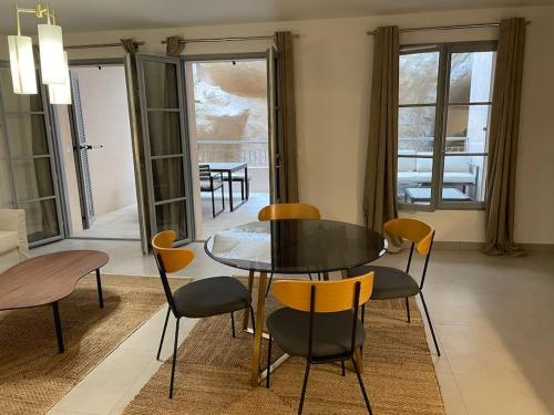 une salle à manger avec une table et des chaises en verre dans l'établissement Superbe T2 neuf Bonifacio avec parking gratuit, à Bonifacio