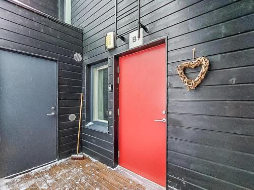 a red door with a heart wreath on a black wall at Holiday Home Skivillas 61 ukkohalla - b1 by Interhome in Hyrynsalmi