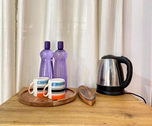 dwie fioletowe butelki i dwie filiżanki na drewnianym stole w obiekcie Mango Villa w mieście Varkala