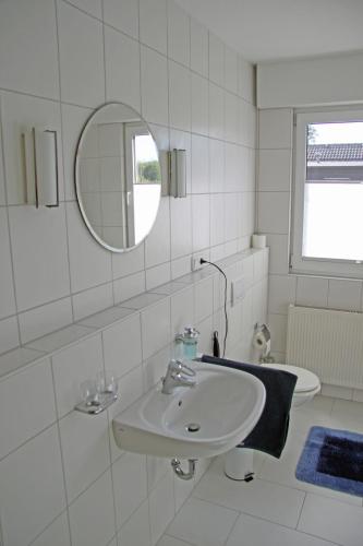 a white bathroom with a sink and a mirror at Ferienwohnung Brandheide in Recklinghausen