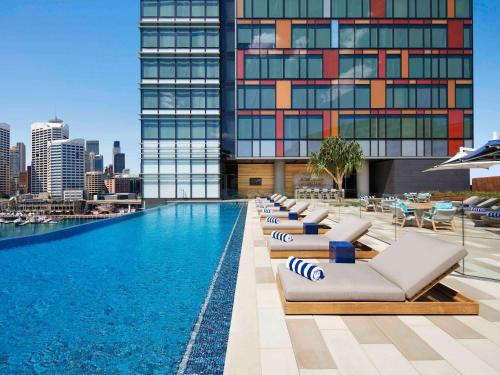 uma piscina do hotel com espreguiçadeiras e um edifício em Sofitel Sydney Darling Harbour em Sydney