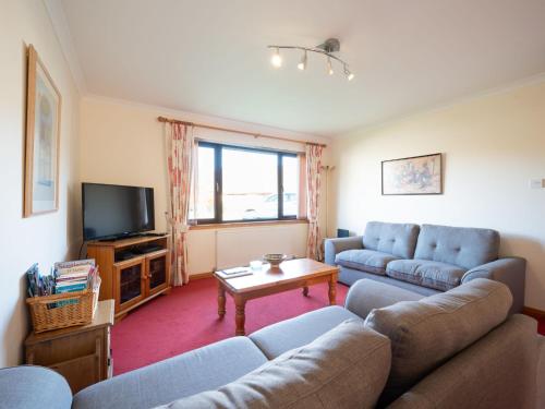 sala de estar con sofá y TV en Holiday Home Glenloch Cottage by Interhome, en Drumnadrochit