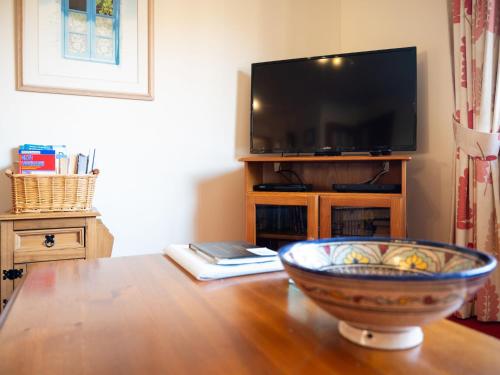 salon z drewnianym stołem z miską na telewizorze w obiekcie Holiday Home Glenloch Cottage by Interhome w mieście Drumnadrochit
