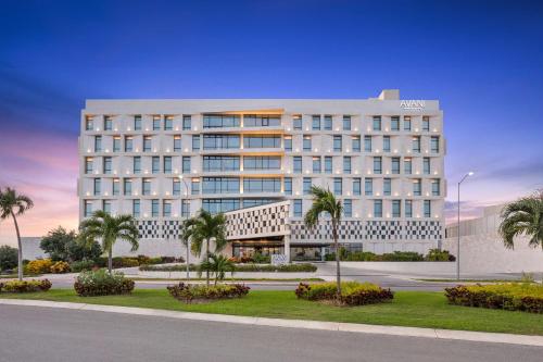 a large white building with palm trees in front of it at Avani Cancun Airport -previously NH Cancun Airport- in Cancún