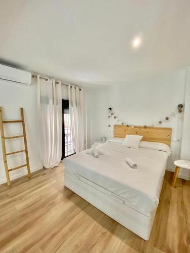 - une chambre avec un lit blanc et du parquet dans l'établissement Loft Alameda en Sevilla, à Séville