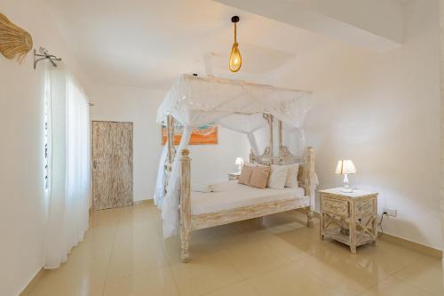 een slaapkamer met een hemelbed en een nachtkastje bij Fully Furnished 2 Bedroom Apartment along Diani Beach Road in Diani Beach