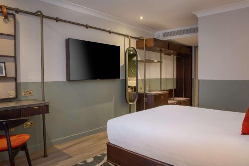 um quarto com uma cama e uma televisão de ecrã plano em The Samuel Ryder Hotel St Albans, Tapestry Collection Hilton em Saint Albans
