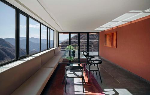 a dining room with a table and chairs and windows at Commune by the Great Wall, in the Unbound Collection by Hyatt in Yanqing
