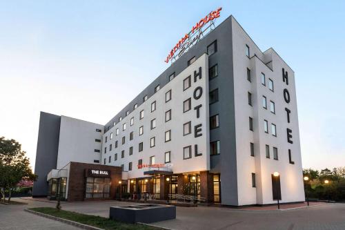 a white building with a sign on top of it at Vienna House Easy by Wyndham Bucharest Airport in Otopeni