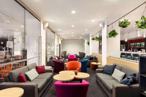 a lobby with couches and tables and a bar at Vienna House Easy by Wyndham Bucharest Airport in Otopeni