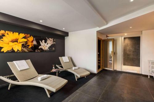 a living room with two chairs and a painting on the wall at Vienna House Easy by Wyndham Bucharest Airport in Otopeni