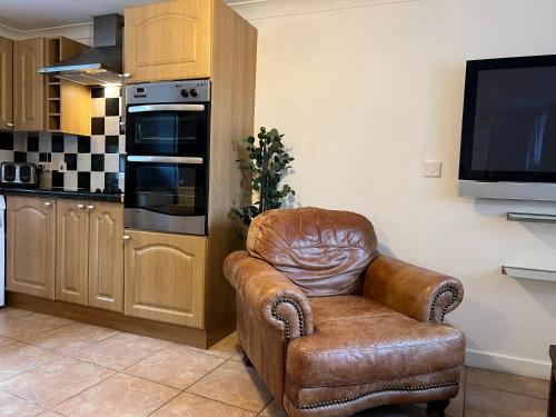 a brown leather chair in a kitchen with a television at Tregib Mill Cottage in Ffair-fâch