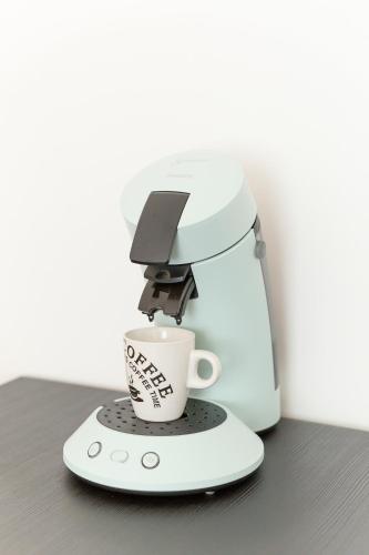 a coffee maker with a coffee cup on a counter at Studio lumineux Maisons-Laffitte in Maisons-Laffitte