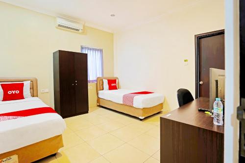 Habitación de hotel con 2 camas y escritorio en OYO Flagship 91290 Pondok Inap Shofwa 2 en Dares