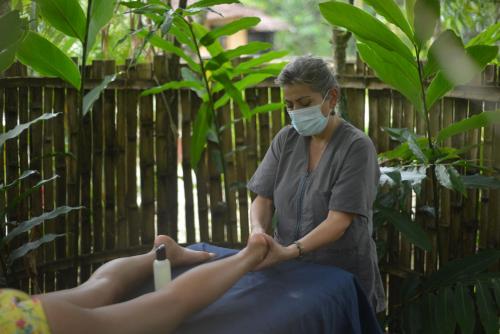 a woman in a face mask treating a persons leg at Casa Vitall in Líbano