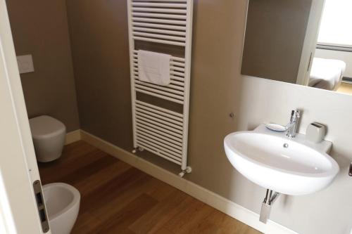 een badkamer met een wastafel, een toilet en een spiegel bij Albergo '900 in Quattordio